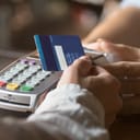 A person paying with a credit card at a POS terminal