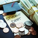 A post-it note saying "student debt" next to some money