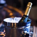 A closeup of a metal bucket with ice and champagne bottle