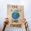 Activist holding up banner 'One Planet One Chance', advocating for environmental action and addressing the global warming crisis.