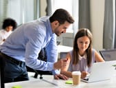 Man overseeing a woman at workplace