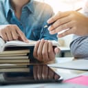 young student on campus tutoring and helping a friend catch up on learning