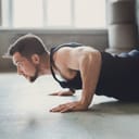 A Caucasian guy doing a plank or push-ups on the floor.