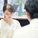 A woman silently looking down with a man sitting opposite her