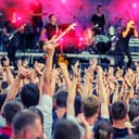 Large crowd of fans with their hands in the air at a live music concert