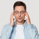 A young man with his eyes closed, slowly exhaling trying to calm himself down