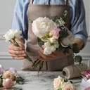 Close-up view of a florist arranging a beautiful bouquet on a white marble table