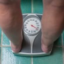 A person standing on a scale pointing at 250kg