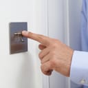 A close-up shot of a man's hand turning off a light switch.