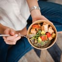 A closeup of a woman eating a meal with fish and vegetables