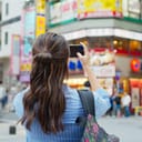 back view of a female backpacker taking photos of Tokyo city with her smartphone
