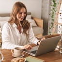 Young woman working on laptop at table indoors