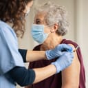 A nurse giving a vaccine to a senior woman