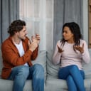 couple arguing about something while sitting on a couch in their living room