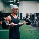man in black tank top and white cap holding black and gray dumbbell
