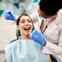 Young smiling woman having her teeth checked by dentist during appointment at dental clinic.
