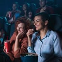 Group of cheerful people laughing while watching movie in cinema.