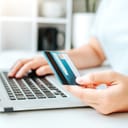 A person making an online purchase using a laptop a holding a credit card