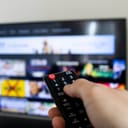 A person holding a remote control watching a streaming service