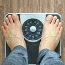 A person weighing themselves on a mechanical scale