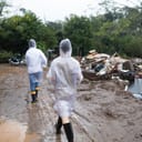 two volunteers in raincoats delivering donations to flood-affected families 