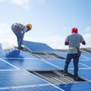 Two handymen installing solar panels on a roof