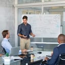 Company executive presenting new management strategy to team in conference room. Successful business man giving reports to his colleagues. Young manager presenting on white board his business plans.