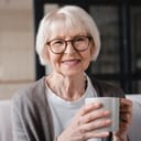 a portrait of a senior woman drinking a hot beverage in her living room