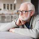 elderly man sitting on the sofa, looking sad and tired at home
