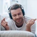Man snapping his fingers with a happy look on his face while listening to music on headphones