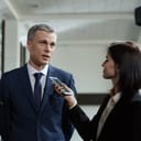 A man in business suit being interviewed by a woman holding a smartphone close to his face