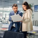 A female employee holding a laptop while her boss is giving her explanations