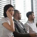 A shy young woman sitting with her coworkers at a meeting
