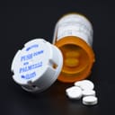 Open bottle of pills lying on black surface