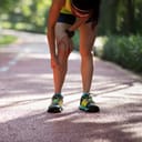 A woman holding her shin on a running track