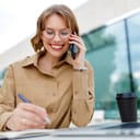 young female office assistant smiling while talking on the phone and doodling