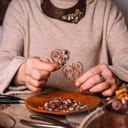 Woman making handmade jewelry out of copper wires and beads