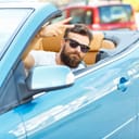 A young bearded man sitting in a convertible - - the concept of buying a used car or a rental car