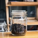 Airtight jar half full of dark roast coffee beans