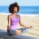 Young woman meditating on a stone wall near the beach