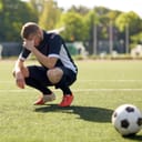 Disappointed soccer player crouching on the pitch