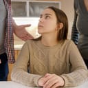Parents standing over a young girl and lecturing her