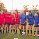 Two women's soccer teams standing next to each other on the pitch