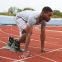 Man gets ready to run on a running track.