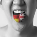 Black and white photo of a person holding their tongue out which is half dyed in the color of German flag and half UK flag