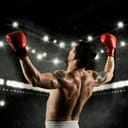 A boxer celebrating a win with his hands high up in the air