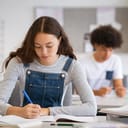 female high school student taking notes from a book, studying at a desk in the college library