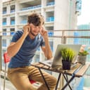 Man sitting on the balcony of an apartment next to a construction site being unable to work because of noise