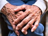 Old person's hands resting on their knee