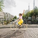 A joyful woman riding a bike down a street in Amsterdam.